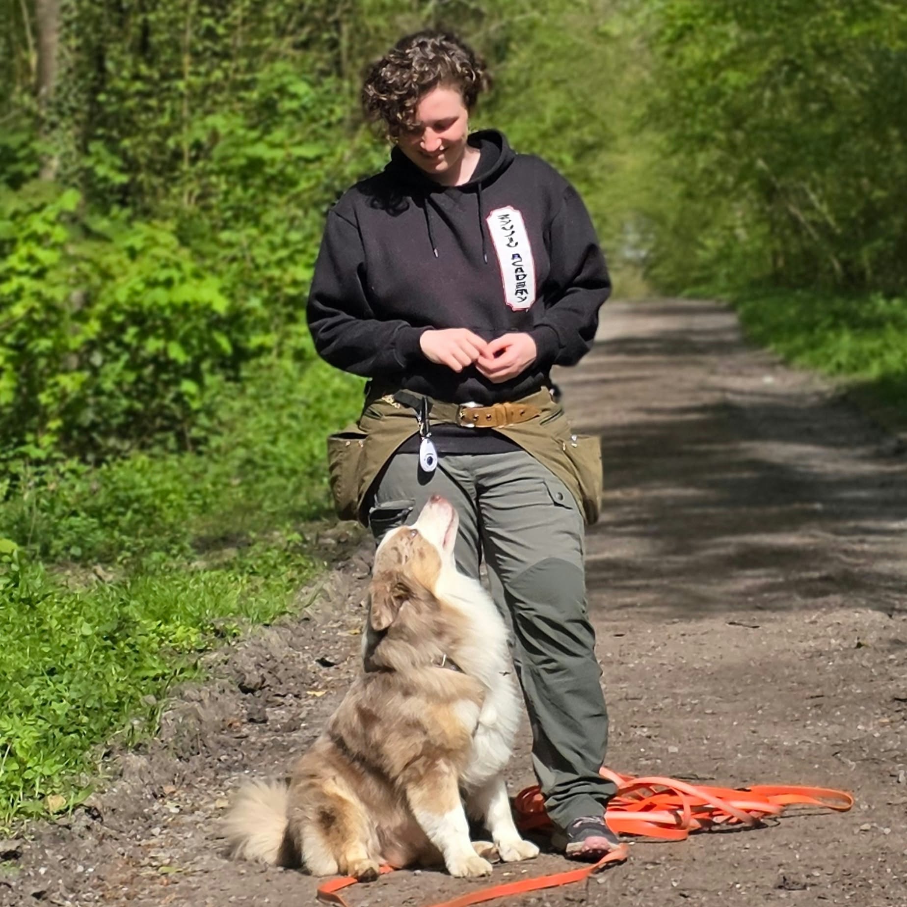 Précila échange avec un chien assis lors d'une séance en extérieur